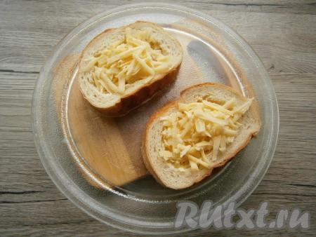 Если яйцо будет немного вытекать, тщательнее придавите края бутербродов. Отправить бутерброды с колбасой и сыром в микроволновку на 3 минуты при мощности 750 Ватт. После этого вынуть горячие бутерброды и сразу посыпать сверху 30-40 граммами натертого твердого сыра.