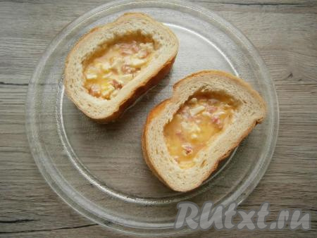 Смазать массой из колбасы и сыра каждый целый ломоть батона так, чтобы в середине её было больше. Накрыть каждый смазанный ломоть батона ломтем с вырезанной серединой (как на фото). Ломти выложить на тарелку из микроволновки. Залить середину взбитым яйцом.
