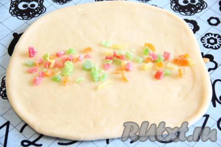 Готовое тесто обмять и разделить на части. Размер куличей выбирайте сами. Можно, подмешав в тесто цукаты, выложить его в формы для выпечки, заполняя их на 2/3. Я решила сделать интересные куличи, сформировав их в форме улиток. Для этого тесто, замешанное на топленом молоке, я разделила на 5 частей. На столе, присыпанном мукой, раскатать одну часть теста в не тонкий прямоугольный пласт, смазать растительным или сливочным маслом, на середину выложить цукаты.