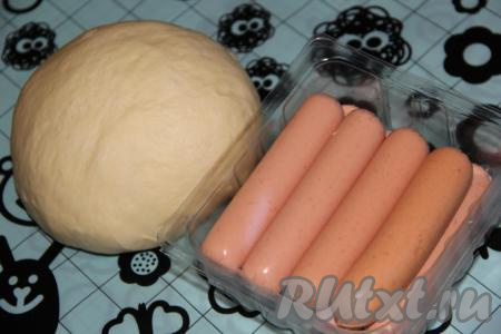 Тесто выложить на стол, хорошо обмять, оставить отдохнуть на 30 минут под полотенцем. По истечении времени очистить сосиски от плёнки.