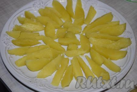 Картофель и яйца нарезаем на крупные продольные дольки. На большое блюдо выкладываем дольки картофеля.