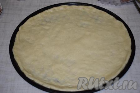 Достаем тесто из миски и распределяем его равномерно по форме, в которой будет выпекаться пицца (при желании, форму можно смазать маслом или застелить бумагой для выпечки). Я использую большую форму диаметром 34 см.