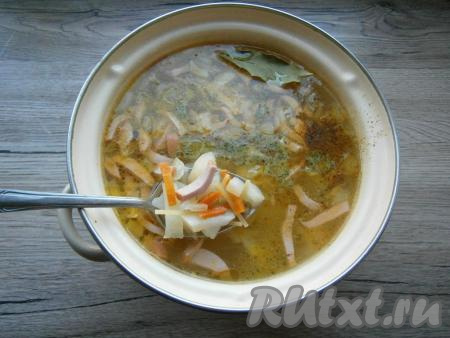 Когда картофель будет почти готов, добавить в кастрюлю обжаренные лук с морковью, колбасу и вермишель. Также добавить лавровый лист, специи, приправу для супа и измельченный очищенный чеснок. Потомить суп на слабом огне еще минут 10.