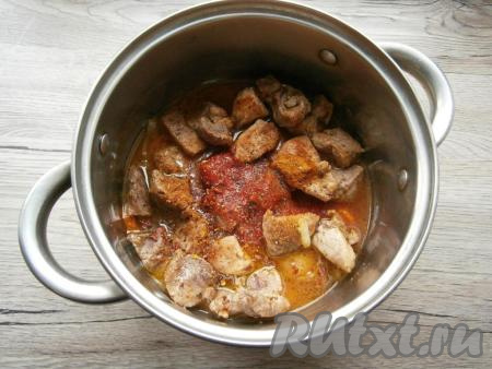 В кастрюлю со свининой, морковью и луком добавить томатную пасту, всыпать соль по вкусу, добавить еще немного специй и красный молотый перец, влить горячую воду (мясо должно быть покрыто водой, практически полностью). Добавить чуть сахара и тушить мясо с овощами на небольшом огне с прикрытой крышкой 40-45 минут с момента закипания. Готовое мясо должно стать мягким (оно будет легко прокалываться вилкой).