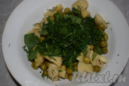 Мелко нарезанную зелень выкладываем в салат из консервированных шампиньонов и горошка.