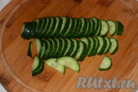 Огурцы нарезаем пополам вдоль и затем - поперек на тоненькие полуколечки.