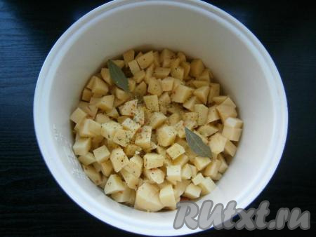 В чашу выложить нарезанный кубиками очищенный картофель, добавить соль, специи, лавровые листья.
