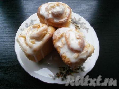 Горячие булочки смазать любой глазурью или растопленным шоколадом. У меня - белковая глазурь, для ее приготовления нужно взбить венчиком белок сырого небольшого яйца, подсыпая постепенно сахарную пудру, перемешивать массу ложкой до нужной вам консистенции, затем влить 1 чайную ложку лимонного сока, хорошенько глазурь растереть.