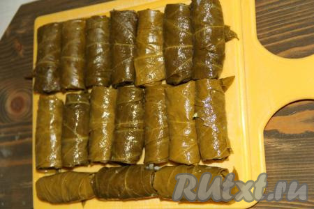 Если используете соленые листья винограда, тогда их следует промыть под проточной водой и выложить в дуршлаг, чтобы удалить излишки воды. Если используете консервированные (маринованные) листья винограда, тогда их следует переложить в глубокую емкость и залить водой. Если через 30 минут листья все еще будут сильно отдавать уксусом, тогда залейте их свежей порцией воды и оставьте еще на 15 минут. В центр каждого подготовленного виноградного листа выложить начинку и завернуть конвертиком (также, как вы заворачиваете фарш в капустные листья, когда готовите голубцы). Я использовала специальное устройство для заворачивания долмы - долмер, поэтому получились ровные и красивые рулетики.