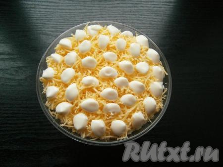 И последним слоем выложить натертый также на средней терке твердый сыр. По всей поверхности нанести капли майонеза.