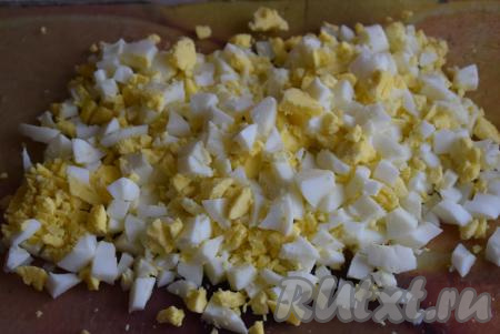 Для приготовления классического салата "Оливье" сначала надо сварить яйца вкрутую (яйца нужно полностью залить водой и варить 10 минут с момента закипания), затем охладить, очистить их от скорлупы и нарезать мелкими кубиками.