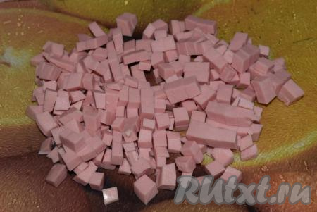 Нарезать колбасу мелкими кубиками.