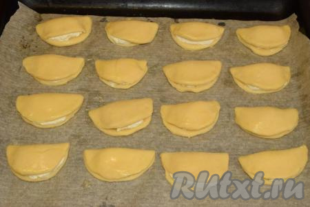 Выкладываем сочни на противень, застеленный пергаментной бумагой, и кулинарной кистью смазываем поверхность (тесто) наших домашних сочней с творогом.