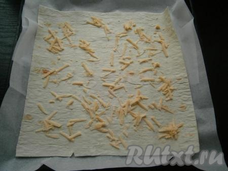 Противень застелить пергаментом, выложить на него лист лаваша. Грамм 15 сыра натереть на крупной терке и посыпать лаваш.