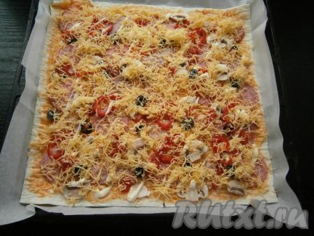 Оставшийся сыр натереть на средней или мелкой терке и щедро посыпать пиццу сверху.