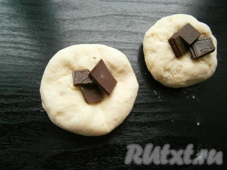 Тесто, разделив на 12-14 частей, скатать в шарики. Каждый шарик распластать в лепешку, в центр выложить по несколько кусочков поломанного шоколада.