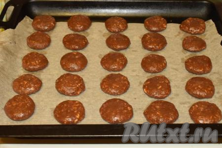 Придаем кусочкам теста сначала круглую форму, а затем расплющиваем между ладонями, придавая вид печенья. Выход печенья по этому рецепту - 25 штук. Выкладываем овсяно-шоколадное печенье на противень, застеленный пергаментной бумагой.