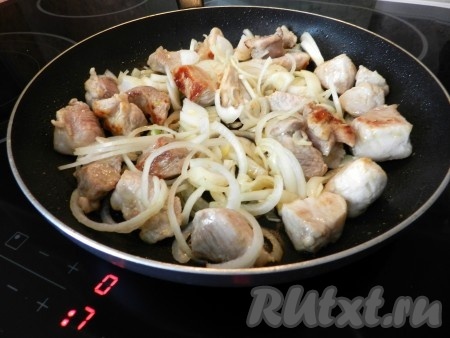 К обжаренной свинине добавить лук, перемешать, обжаривать 3-4 минуты на среднем огне, периодически перемешивая.