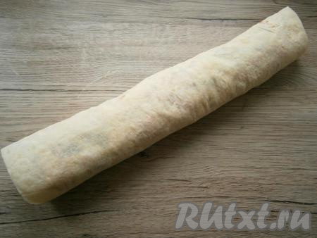 Лаваш плотно свернуть в рулет и, завернув в пищевую пленку, поместить в холодильник на 30-40 минут.