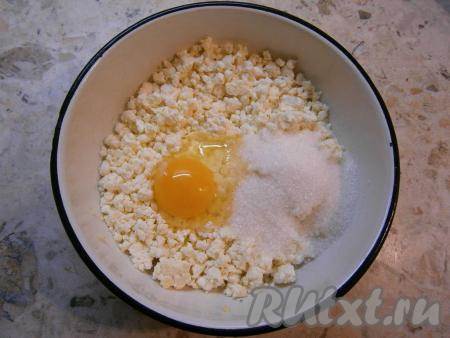 В творог добавить щепотку соли, сырое яйцо и всыпать сахар.