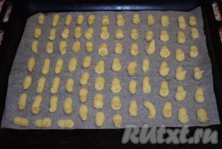 Отсаживаем&nbsp;тесто небольшими порциями на противень, застеленный пергаментом. Тесто отсаживаем на небольшом расстоянии друг от друга (как на фото), так как "пальчики" увеличатся в объёме в процессе выпечки.