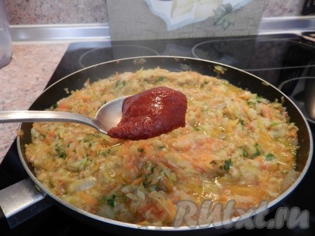 Добавить нарезанную зелень и томатную пасту, перемешать, уменьшить огонь и тушить кабачковую икру с помидорами 30-40 минут до полного размягчения.
