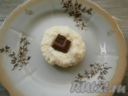 Тесто получится липким, но муки больше добавлять не нужно, чтобы сырники получились нежными. Сформировать влажными руками небольшие лепёшки, в середину которых поместить по кусочку шоколада. Затем слепить из этих лепёшек сырники, чтобы шоколад оказался внутри.