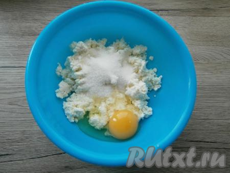 В творог добавить яйцо, щепотку соли, всыпать сахар.