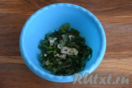 Выкладываем нарезанную зелень в миску, добавляем чеснок, пропущенный через чеснокодавилку.