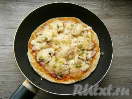 Поставить сковороду на небольшой огонь, накрыть крышкой. Готовить ленивую пиццу около 10 минут, затем посыпать измельченным зеленым луком.