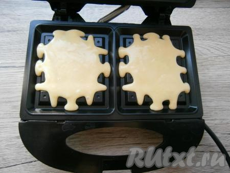 Электровафельницу хорошо разогреть, в центр ячеек равномерно выложить по 2 столовые ложки теста, крышку закрыть.