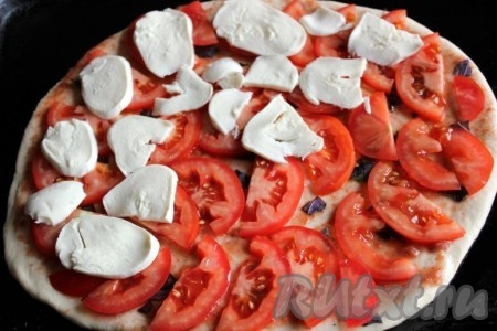 На слой помидоров нужно разложить дольки моцареллы, сбрызнуть, примерно, 1 столовой ложкой оливкового масла, дать постоять пицце при комнатной температуре минут 10-15, потом поместить в разогретую духовку и выпекать при температуре 200-220 градусов около 13-15 минут. Пока выпекается первая пицца, аналогично сформировать вторую пиццу, используя вторую часть теста и оставшиеся ингредиенты для начинки.