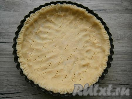 Далее тесто распределить руками по дну круглой формы для выпечки диаметром 20-22 см, формируя бортики. Наколоть тесто вилкой.