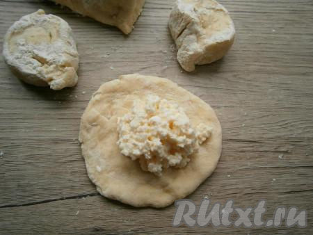 Тесто обмять и разделить его на небольшие кусочки, из каждого - сформировать лепешку. В середину каждой лепешки поместить столовую ложку творожной начинки.