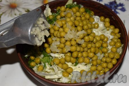 Половину горошка из банки кладем в салатник. Выдавливаем через чеснокодавилку&nbsp;в салат чеснок.