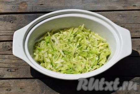 В керамическую форму (или другую форму для выпечки), не смазывая дно маслом, первым слоем равномерно выкладываем половину капусты, смешанной с кабачком.