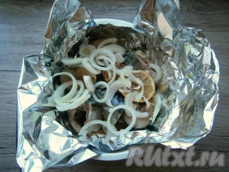 Скумбрию перемешать, оставить на 15-20 минут для маринования, после чего выложить ее вместе с&nbsp; лимоном на лист фольги, сложенный вдвое. Фольгу с рыбой поместить в чашу для варки на пару, подогнув края фольги кверху. На рыбу выложить нарезанный тонкими колечками или полуколечками очищенный репчатый лук.