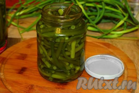 Заливаем чесночные стрелки в банках кипящим маринадом.