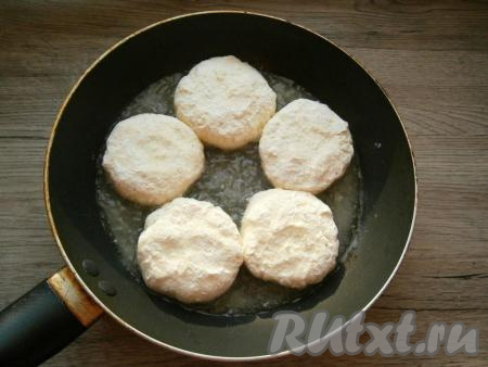 Защипнуть края лепешки, формируя сырник, чтобы ягода была внутри. Аналогично сформировать все сырники с клубникой. Обвалять сырники немного в муке, выложить на сковороду, хорошо разогретую с растительным маслом, и жарить до румяности с двух сторон на среднем огне.