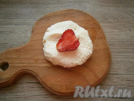 Мокрыми руками сформировать из небольшого количества творожного теста лепешку, в середину которой поместить половинку ягоды клубники.