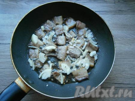 В разогретую сковороду выложить сало в один слой, обжарить на небольшом огне, пока сало чуть не подрумянится и начнет вытапливаться жир. Кусочки сала перевернуть и добавить в сковороду нарезанный репчатый лук. Немного поперчить и, если сало свежее, - посолить.