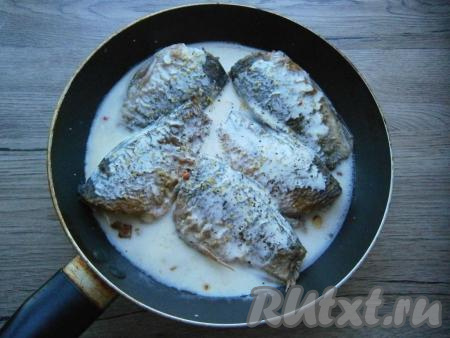 На обжаренный лук выложить жареных карасиков, залить их сметаной, смешанной с водой, посолить и посыпать специями.