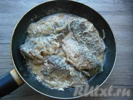 Довести до кипения, огонь убавить до минимального, прикрыть сковороду крышкой. Тушить карасей в сметане минут 15.