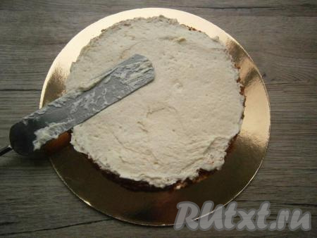 Смазать кремом нижнюю часть бисквита.