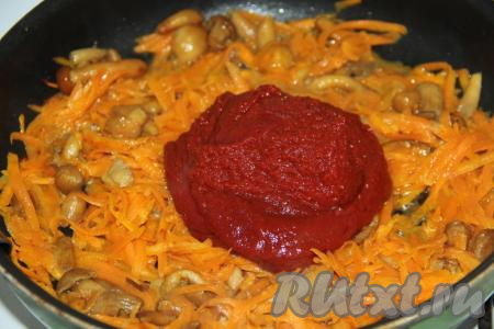 Затем к грибам, обжаренным с морковкой, добавить томатную пасту, тщательно перемешать и обжарить пару минут.
