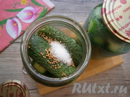 Воду из банок с огурцами слить в раковину и снова залить банки кипятком на 5 минут. Затем и эту воду слить в раковину, а в каждую банку добавить по 0,5 чайной ложки лимонной кислоты и по 1 столовой ложке зерен горчицы.