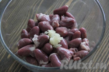 Сердечки промыть под проточной водой, срезать лишний жир и крупные сосуды. Чеснок очистить и пропустить через пресс. Добавить половину чайной ложки соли и чеснок к сердечкам.