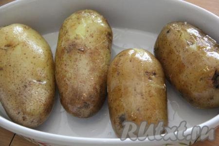 Затем слить с картофеля воду и переложить его в жаропрочную форму. Сбрызнуть картошку растительным маслом и хорошо растереть масло по всей поверхности каждой картофелины. Сделать на каждой картошине крестовидные глубокие надрезы. Поставить форму с картофелем в мундире&nbsp;в разогретую духовку и запекать при температуре 180 градусов, примерно, 25 минут.