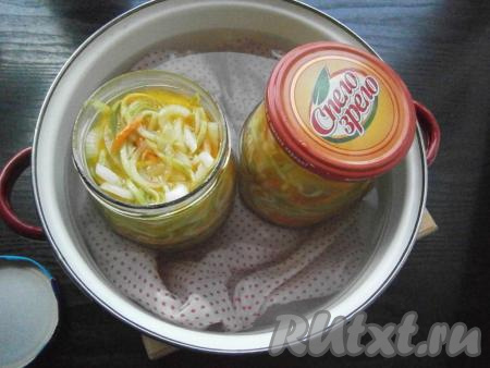 Прикрыть банки прокипяченными крышками. На дно большой кастрюли поместить тряпочку и налить воду, довести ее до кипения и затем осторожно поставить банки с прикрытыми крышками. Стерилизовать салат 20 минут с момента закипания воды в кастрюле на среднем огне.