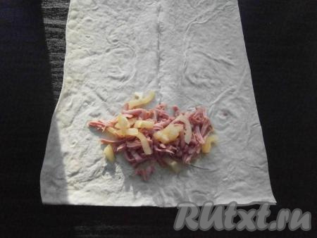 Взять одну часть лаваша, на краю разместить 1-2 столовые ложки колбасы и немного нарезанного болгарского перца (как на фото).